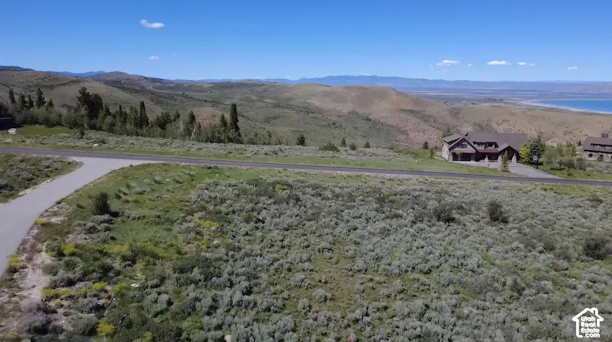 Aerial landscape featuring expansive hillside terrain, native shrubbery, paved roadways, and mountain topography