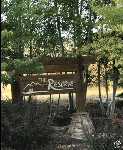 Custom wood signage featuring metal architectural plates, stone pillar base, and surrounding mature aspen trees