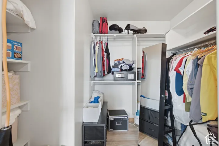Walk-in closet featuring multi-level built-in shelving, integrated garment rods, and wood-finish flooring