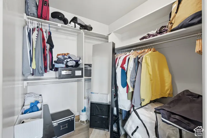 Walk-in closet featuring multi-level built-in shelving, dual-tier hanging rods, and wood-finish flooring