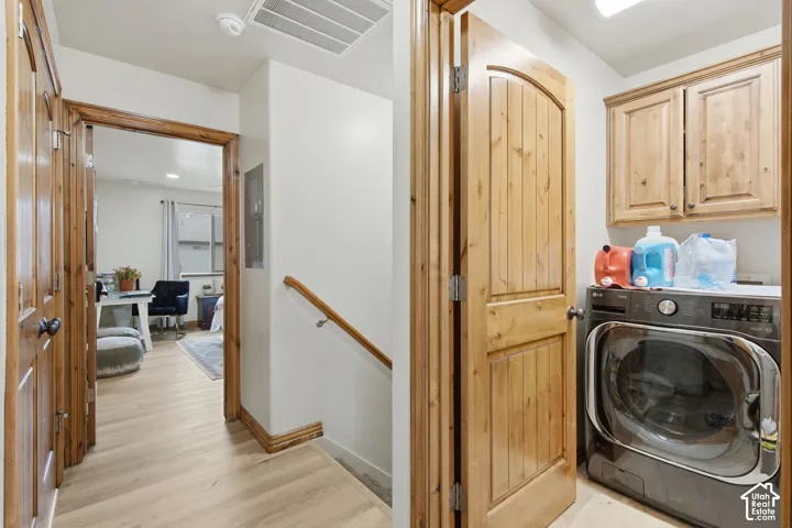 Laundry area featuring built-in wood cabinetry, wood-finish flooring, and natural wood-toned trim and interior doors