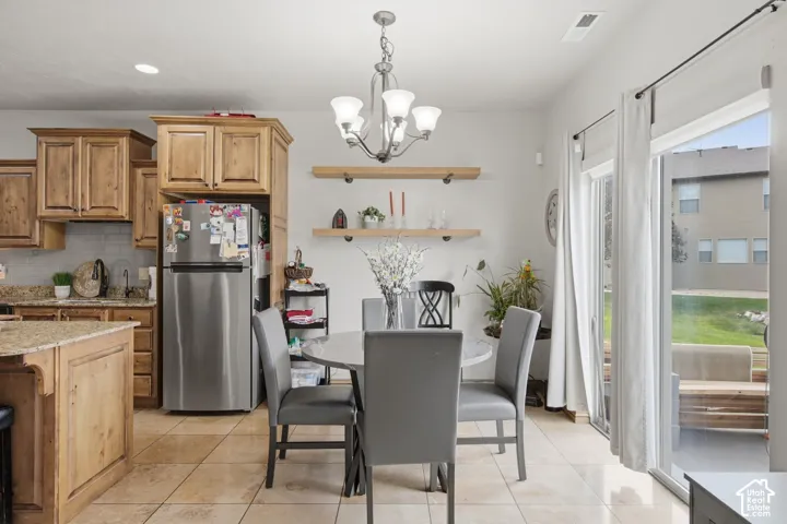 Kitchen featuring stained wood cabinetry, stone countertops, dual floating wood shelves, chandelier lighting, and a sliding glass door