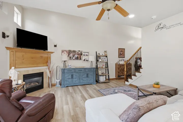 Vaulted ceilings, fireplace with wood mantel, wood-finish flooring, and staircase with iron balusters