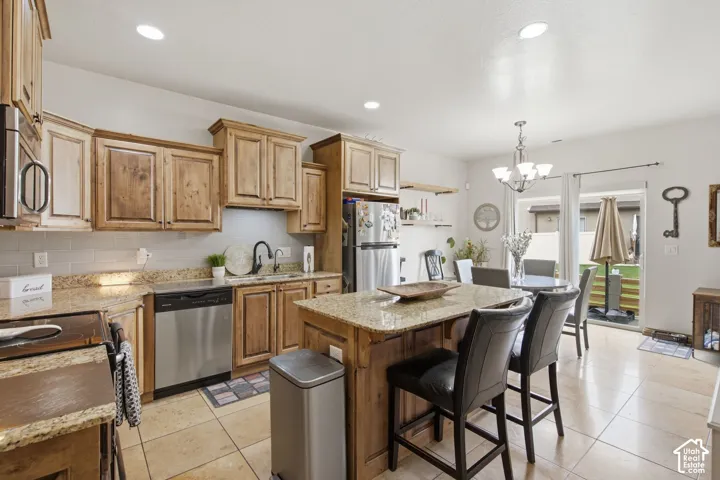 Kitchen featuring stained wood cabinetry, stone-surface countertops, central island, tile flooring, and stainless steel dishwasher