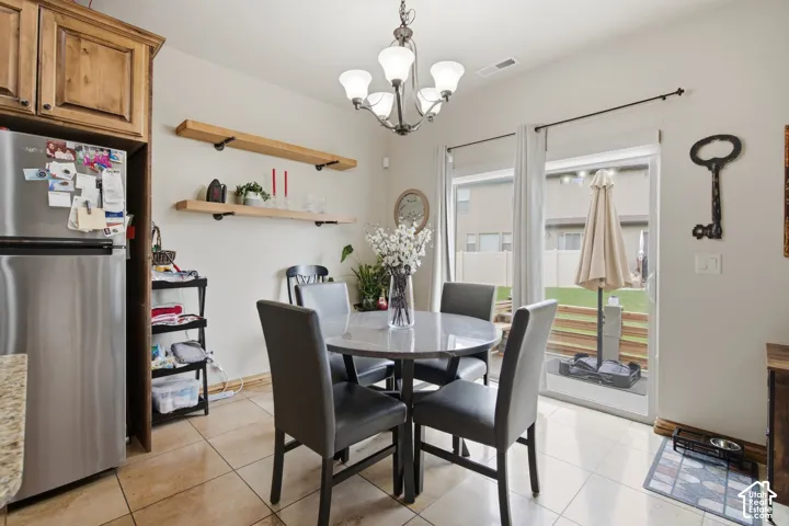 Dining area featuring tile flooring, wood-finish wall-mounted shelving, a multi-bulb chandelier, and sliding glass doors