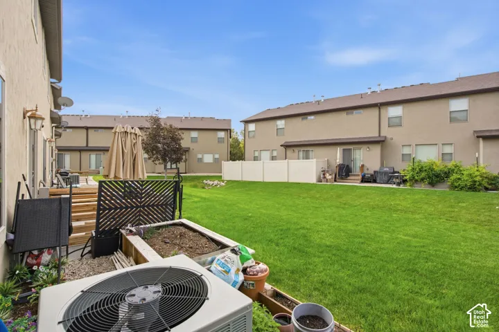 Shared common area featuring a manicured lawn, perimeter fencing, and concrete patios