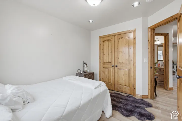 Room featuring wood-finish flooring, dual-panel wood-grain closet doors, recessed lighting, and a flush-mount ceiling fixture
