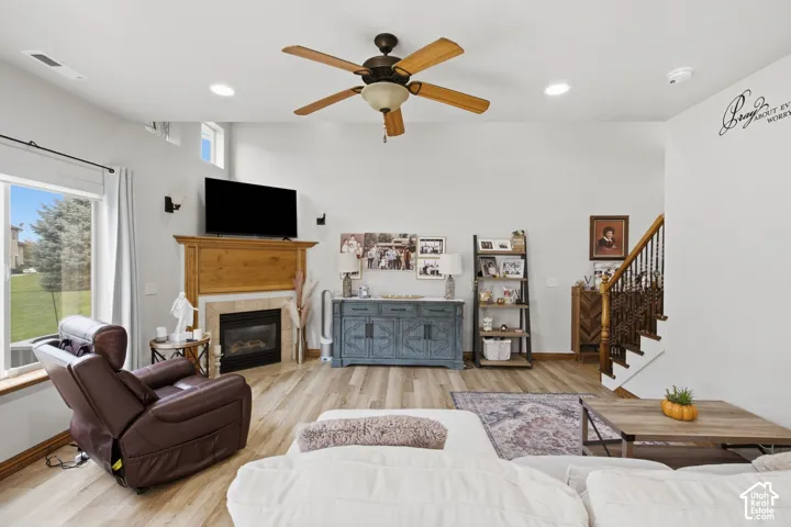 Vaulted ceilings, wood-finish flooring, fireplace with a wood mantel and tile surround, and an open staircase with a decorative metal balustrade