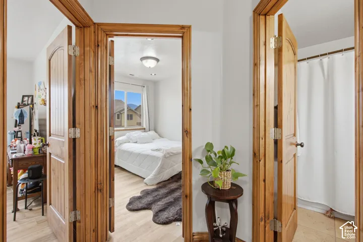 Natural wood-finish interior doors with arched panels, neutral wall finishes, wood-finish flooring, and recessed ceiling lighting