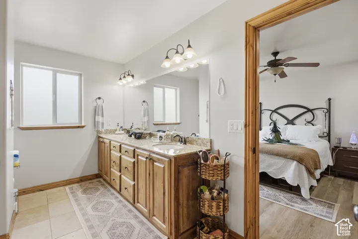 Bathroom vanity featuring wood cabinetry, stone-finish countertops, dual integrated sinks, and wall-mounted light fixtures
