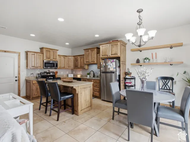 Kitchen featuring stained wood cabinetry, stone-finish countertops, center island, tiled flooring, and dual wall-mounted floating shelves