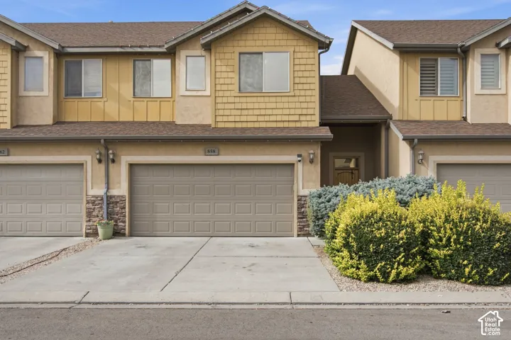 Multi-level exterior featuring stucco and shingle siding, stone veneer accents, an attached two-car garage, and mature landscaping