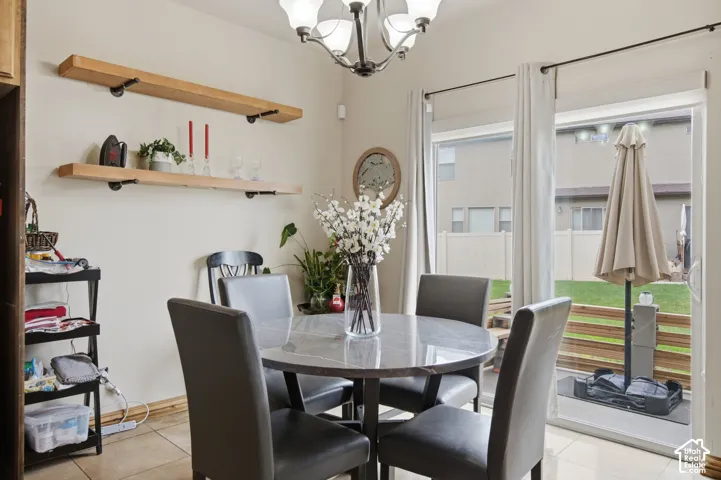 Dining area featuring tile flooring, wall-mounted natural wood shelving, a multi-light chandelier, and a sliding glass door providing external access