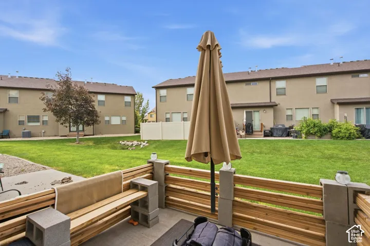 Concrete patio featuring a custom horizontal wood-slat privacy fence with integrated cinder block pillars, overlooking an expansive shared grass lawn