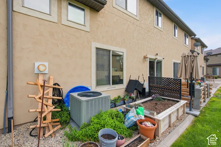 Stucco exterior with multi-pane windows, central air conditioning unit, and elevated timber garden planter