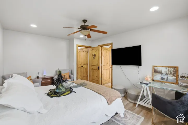 Room featuring wood-finish flooring, recessed lighting, a ceiling fan, and arched-panel knotty wood interior doors