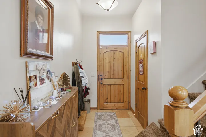 Entryway featuring a solid wood front door with an arched glass transom, stone tile flooring, and a flush-mount light fixture