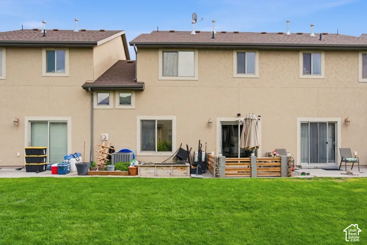 Stucco exterior featuring multiple sliding glass doors and a concrete patio set against a manicured lawn