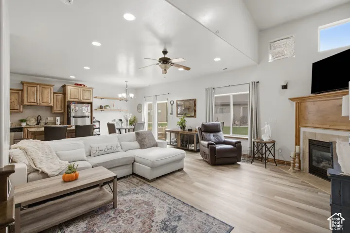 Vaulted ceilings with recessed lighting, wood-finish flooring, built-in cabinetry, ceiling fan, and a fireplace with a stone-surround mantel