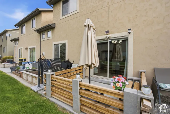 Stucco exterior featuring a concrete patio with a tiered horizontal wood fence and sliding glass door
