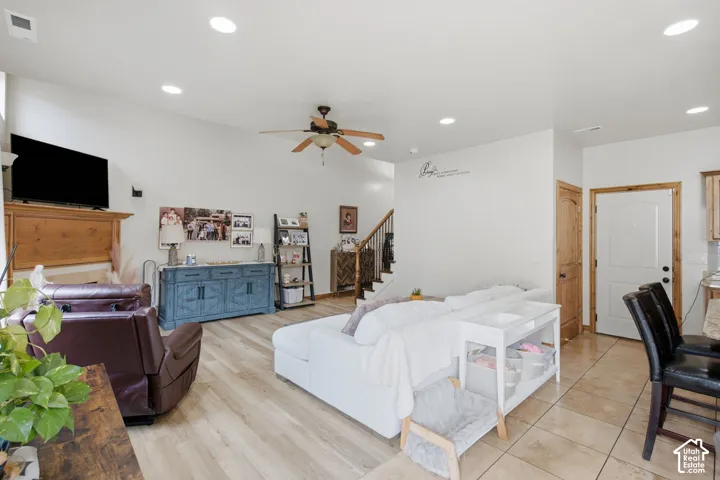 Open-concept interior featuring vaulted ceilings, recessed lighting, wood-finish flooring, a built-in wood fireplace mantel, and a central ceiling fan