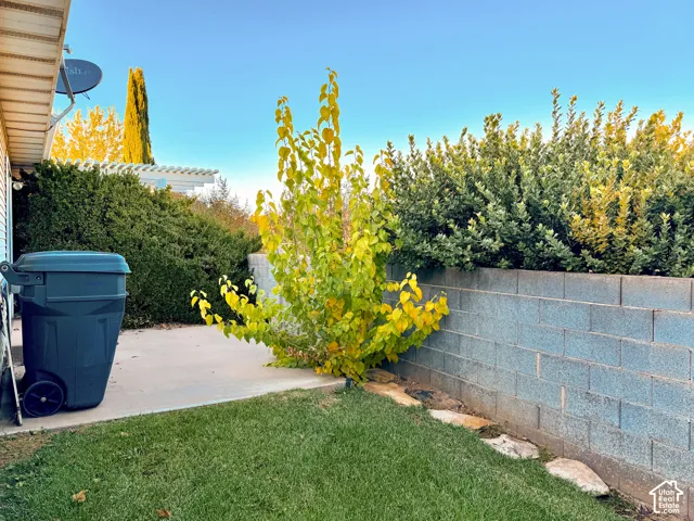 Concrete patio area featuring a stone-bordered garden bed, a block masonry perimeter wall, and mature landscaping