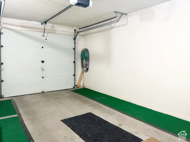 Enclosed garage with concrete flooring, overhead door mechanism, and wall-mounted storage utility