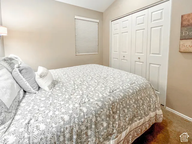 Vaulted ceiling, neutral wall tones, bi-fold closet doors, and a window with integrated blinds