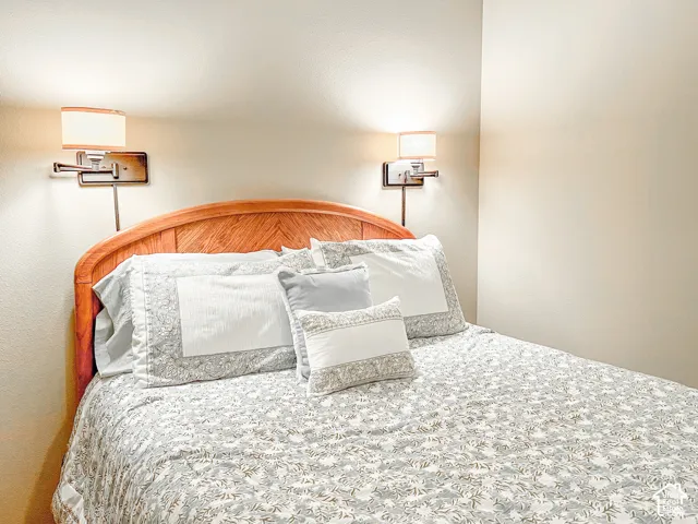 Wall-mounted swing-arm sconces with fabric shades and wood-finish headboard