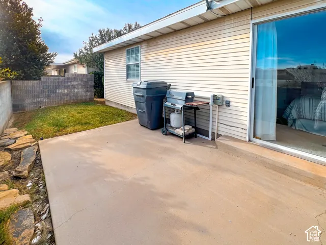 Concrete patio with sliding glass door access, exterior siding, and masonry privacy wall