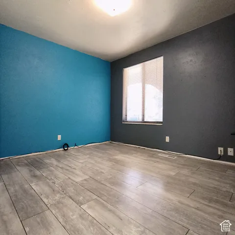 Interior room featuring wood-finish flooring, dual-tone painted walls, and a large window with fitted blinds