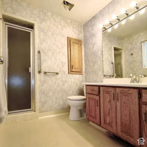 Bathroom featuring a vanity with wood cabinetry, a large wall-mounted mirror, a walk-in shower enclosure, built-in wall cabinetry, and metal safety grab bars