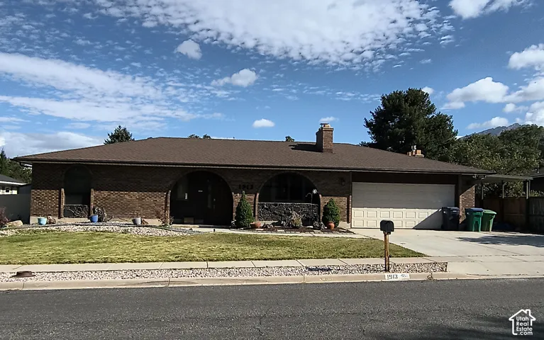 Single-story brick exterior featuring arched entryway detailing, 2 car garage & carport