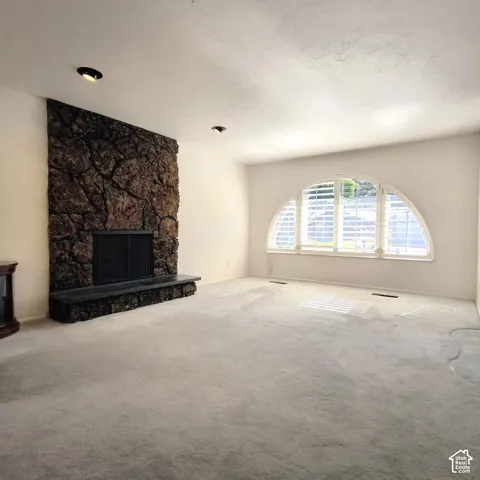 Full-height stone fireplace with a raised hearth and black metal surround, featuring an arched window with integrated shutters and recessed lighting