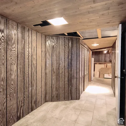 Vertical wood-panel walls, tile flooring, recessed ceiling lighting, and built-in louvered closet doors