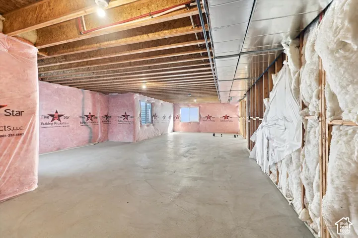 Unfinished area featuring exposed ceiling joists, concrete flooring, exterior wall insulation, and installed metal ductwork