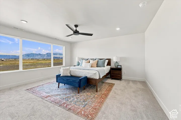 Large windows showcasing mountain scenery, neutral carpeting, recessed lighting, and a dark matte ceiling fan
