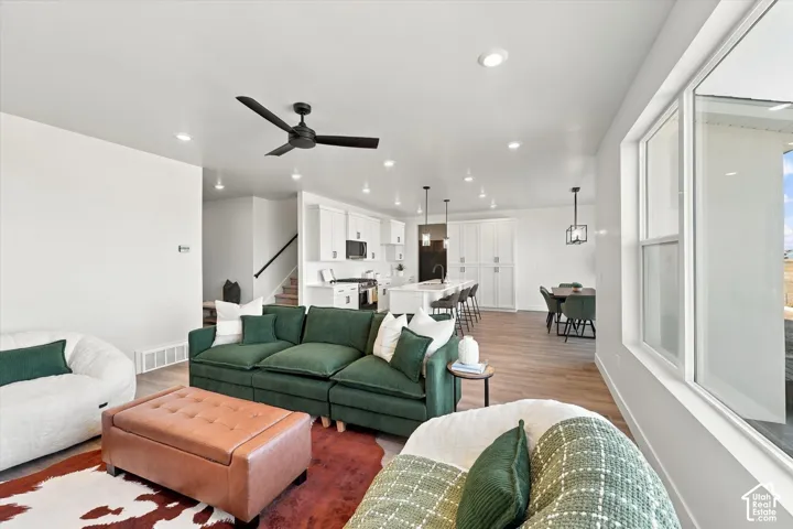 Open-concept interior featuring wood-finish flooring, recessed lighting, a central kitchen island with built-in cabinetry, and large-format windows