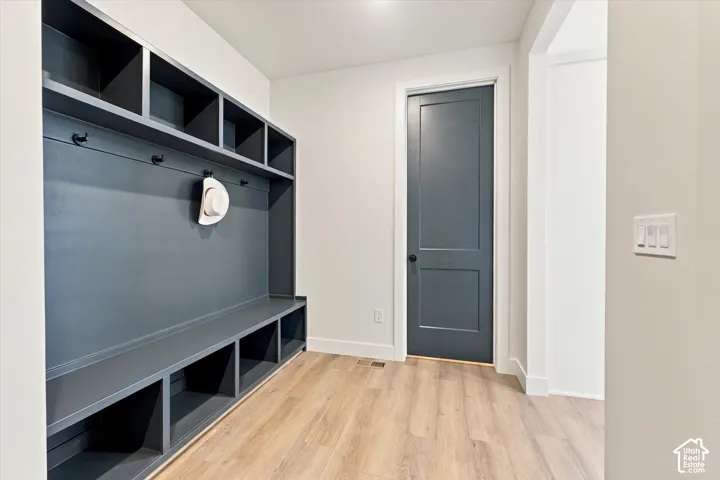 Built-in custom cabinetry featuring open lockers and bench seating, wood-finish flooring, and a solid-core single-panel door with matte black hardware