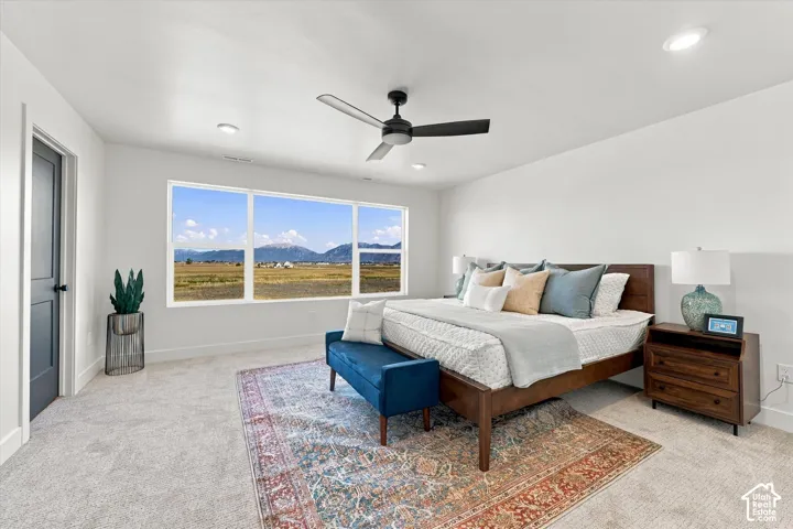 Spacious interior featuring neutral carpeting, a large picture window showcasing a mountain backdrop, recessed lighting, and a modern ceiling fan