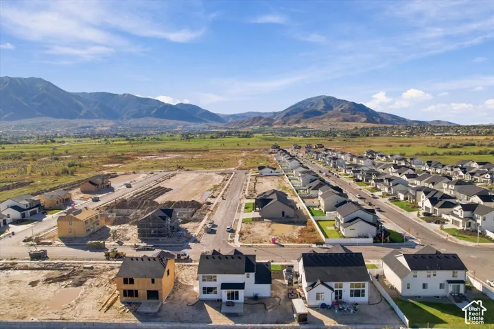 Aerial perspective of a residential development featuring newly constructed homes, paved streets, and a backdrop of expansive mountain ranges