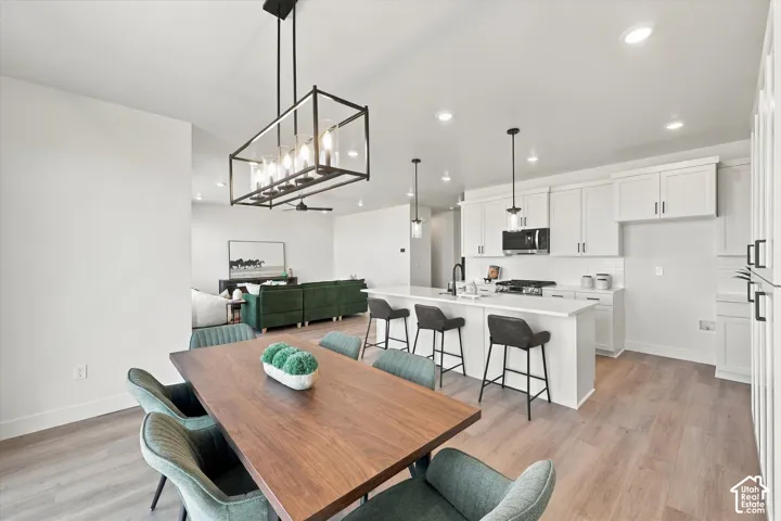 Open-concept kitchen featuring white shaker-style cabinetry, quartz countertops, a central island, recessed lighting, and wood-finish flooring