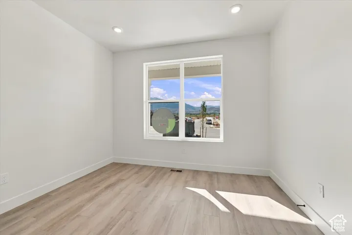 Neutral-toned room featuring wood-finish flooring, recessed lighting, and a window with mountain scenery