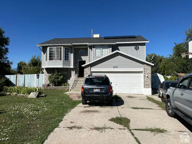 Two-story home featuring horizontal lap siding, brick facade accents, an attached two-car garage, roof-mounted solar panels, and a front bay window