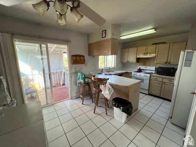 Kitchen featuring ceramic tile flooring, wood cabinetry, a peninsula counter, and sliding glass doors providing outdoor access