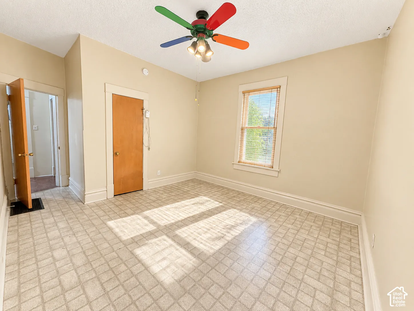 Room featuring patterned vinyl flooring, a single-hung window with wood trim, and solid-core wood doors