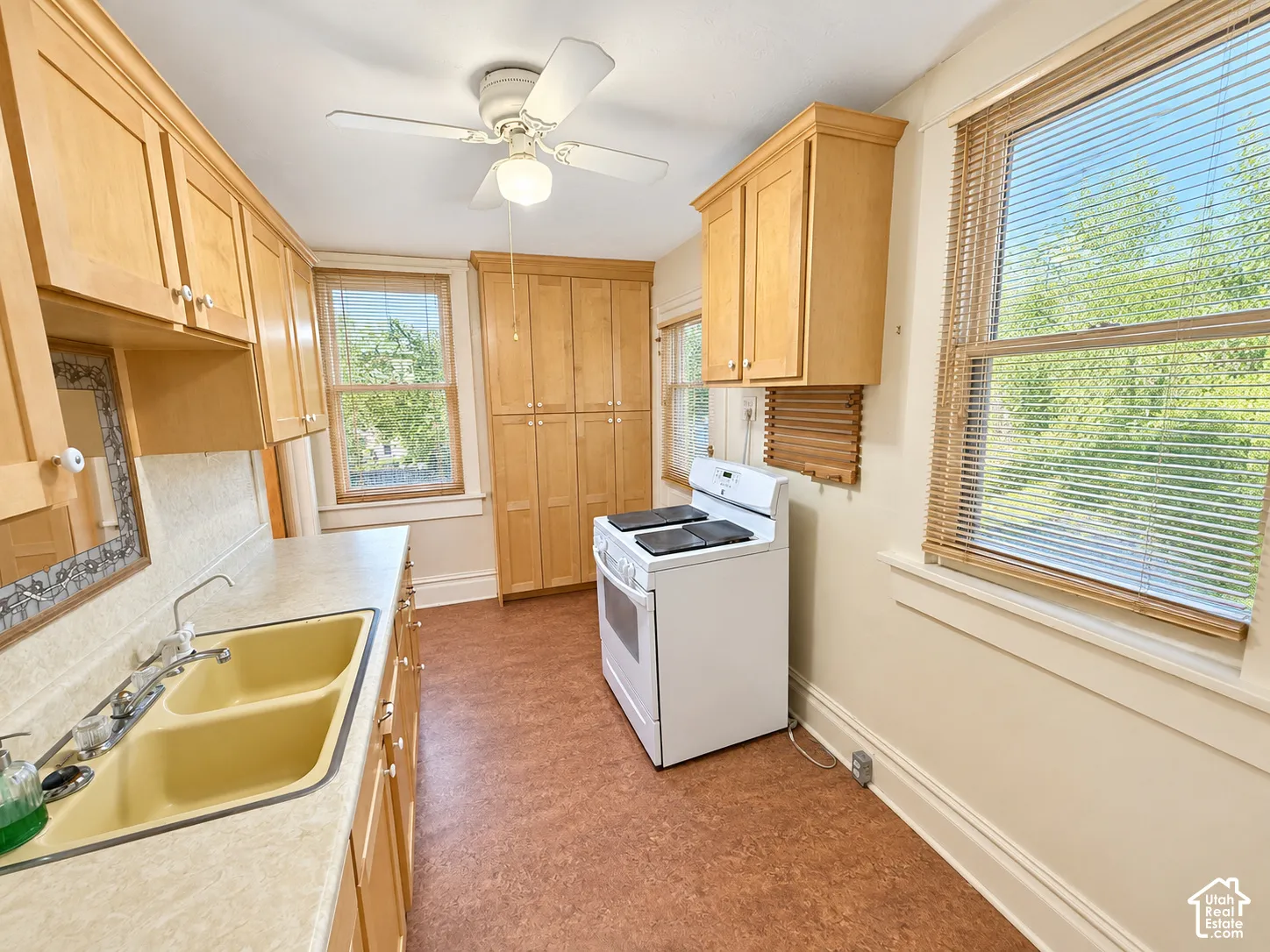 Kitchen featuring natural wood cabinetry, floor-to-ceiling storage, double-basin sink, and multi-paned windows