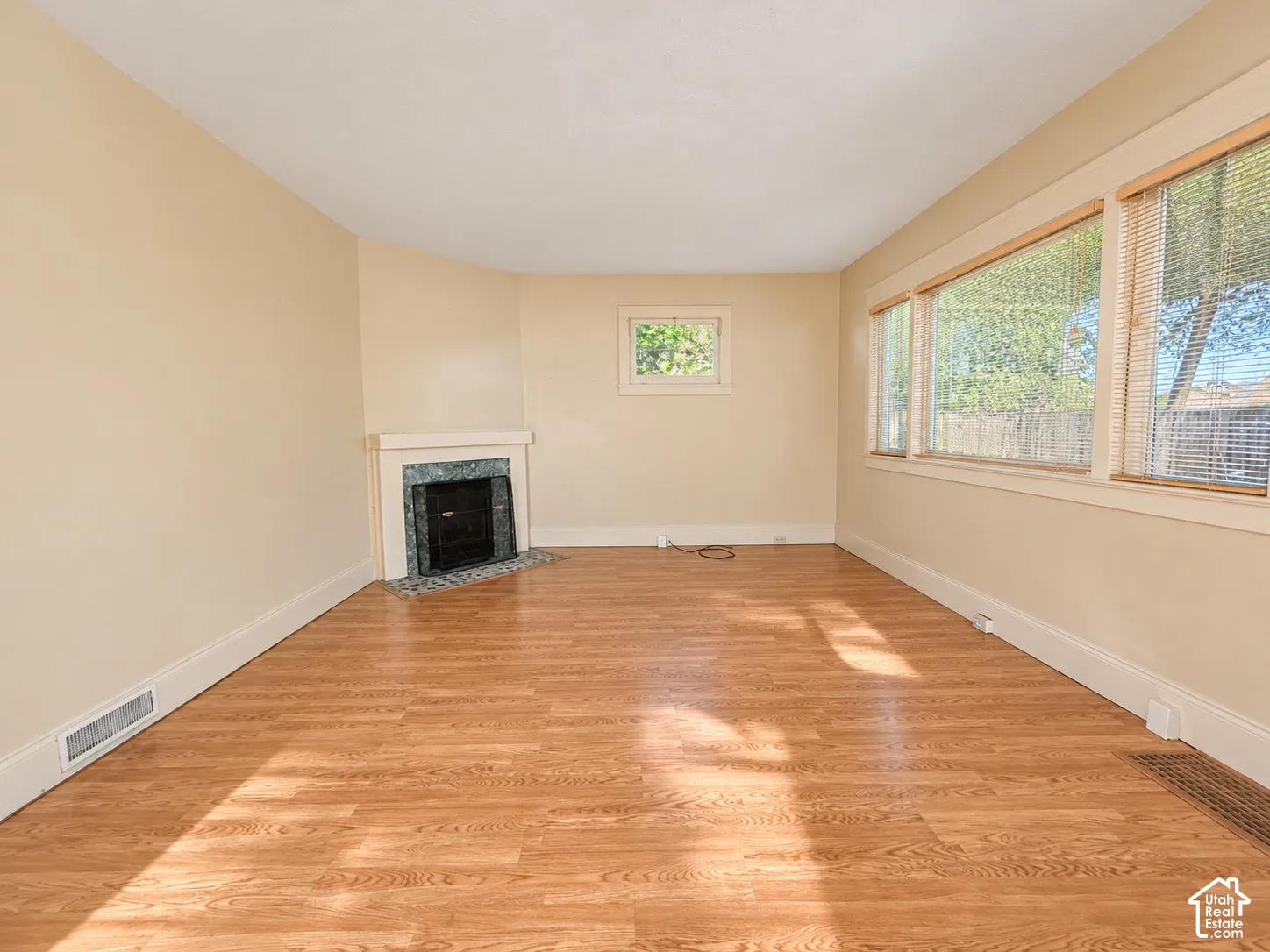 Wood-finish flooring, fireplace with a tile surround and mantel, and large windows with horizontal blinds
