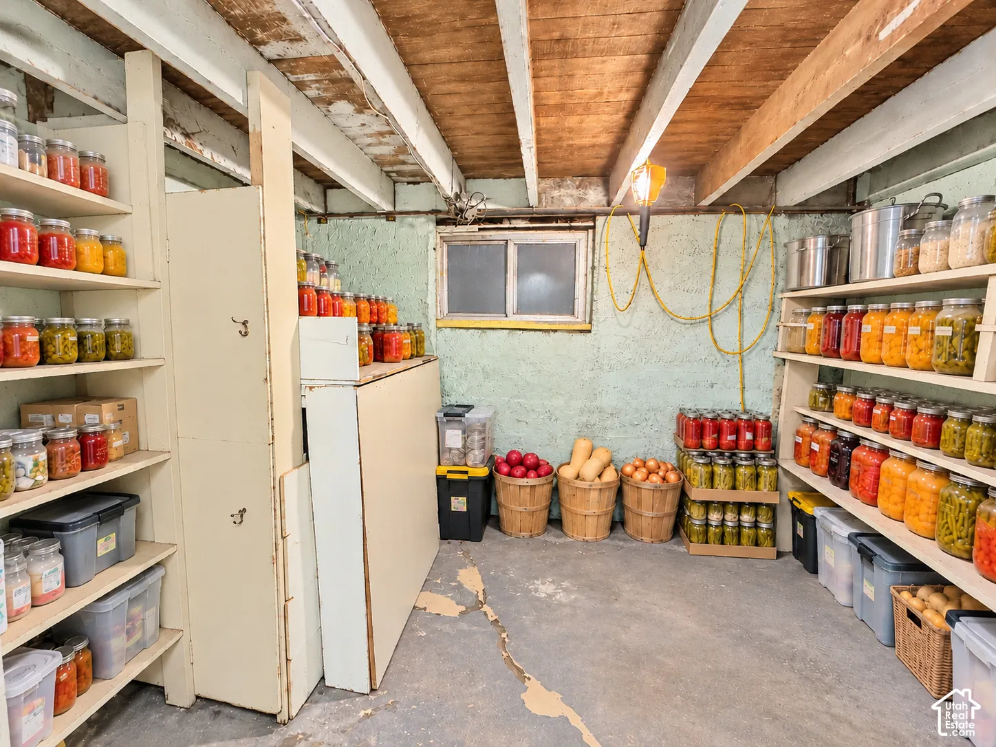 Storage area featuring built-in wooden shelving units, concrete flooring, exposed ceiling joists, and a sliding window