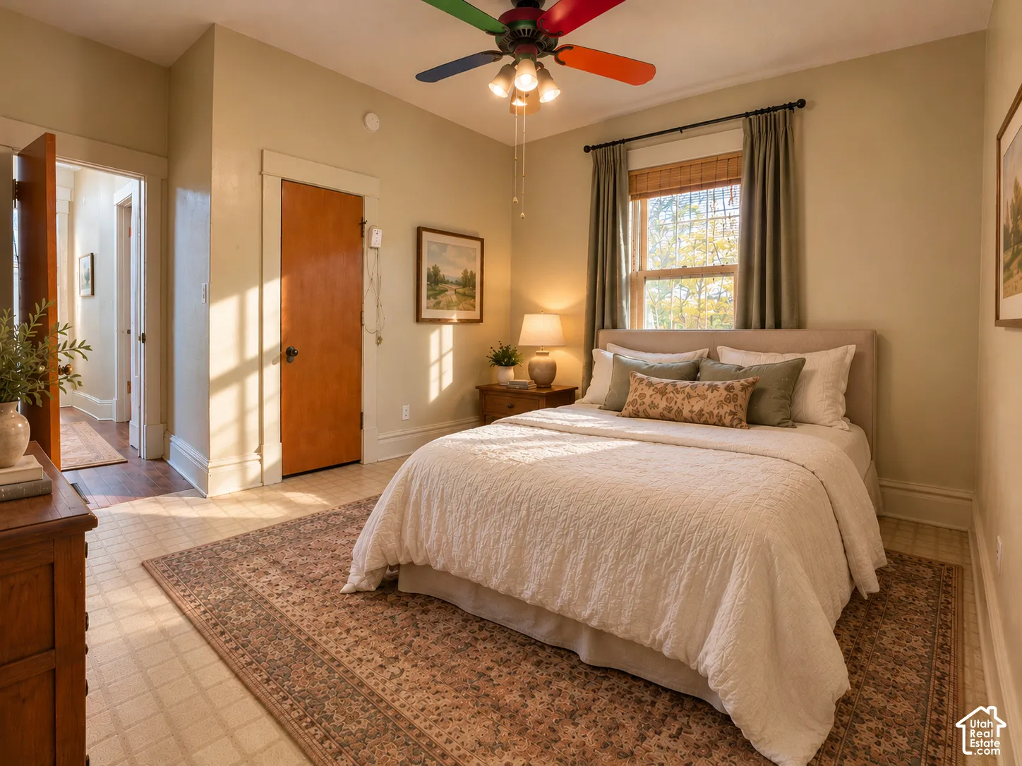 Interior room featuring multi-panel wood door, window with wood-slat blinds, and ceiling fan with multi-colored blades